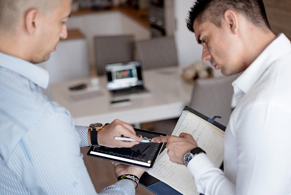 Two professionals reviewing financial charts on a tablet during a business meeting.